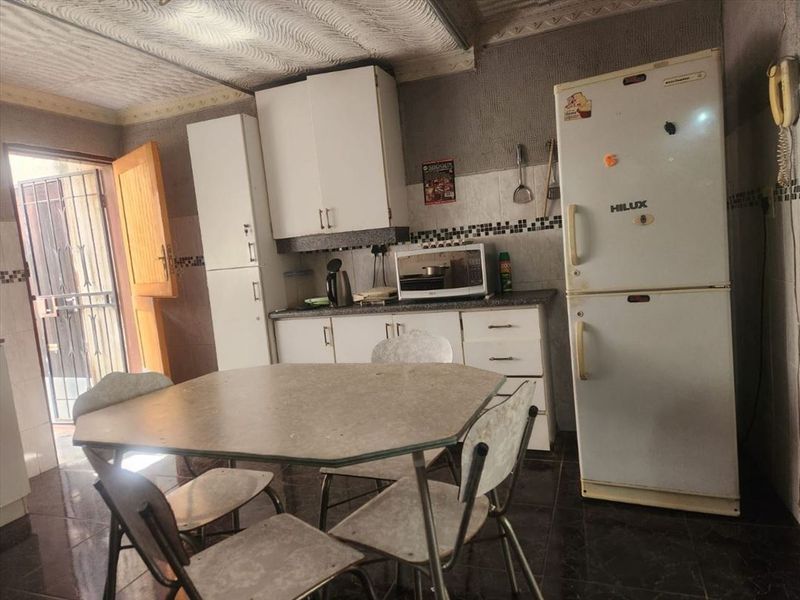 A functional kitchen area featuring built-in cabinetry, tiled backsplash, and direct access to an exterior area through a security gate.