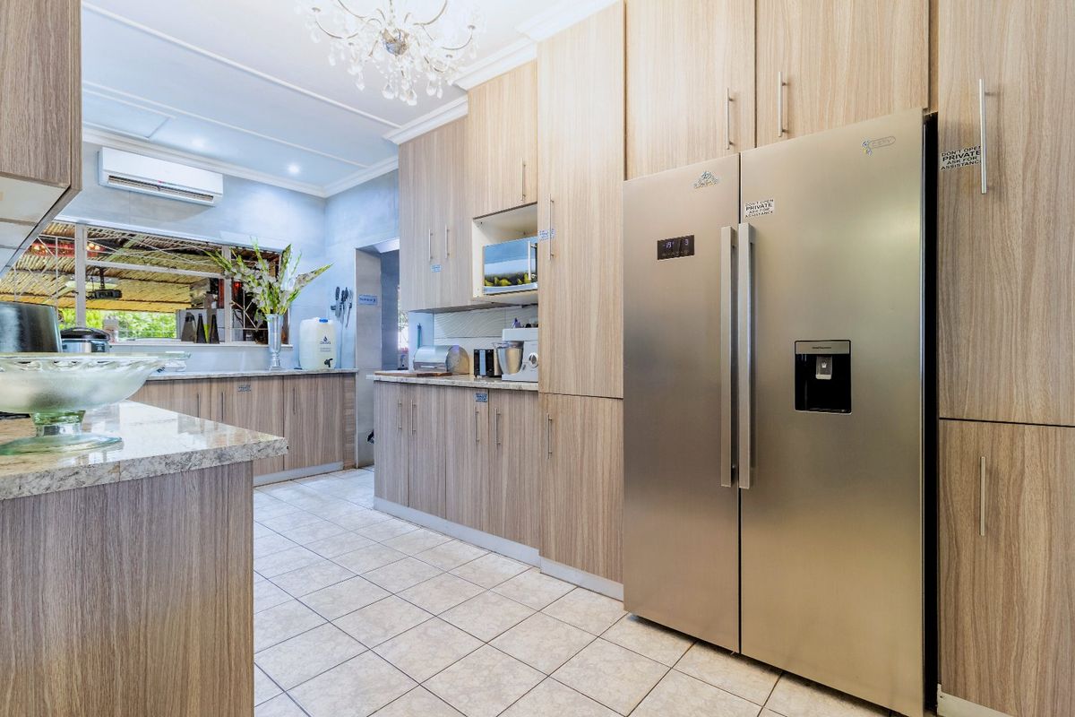 Modern kitchen featuring light wood-grain cabinetry, granite countertops, tiled flooring, and a wall-mounted air conditioning unit.