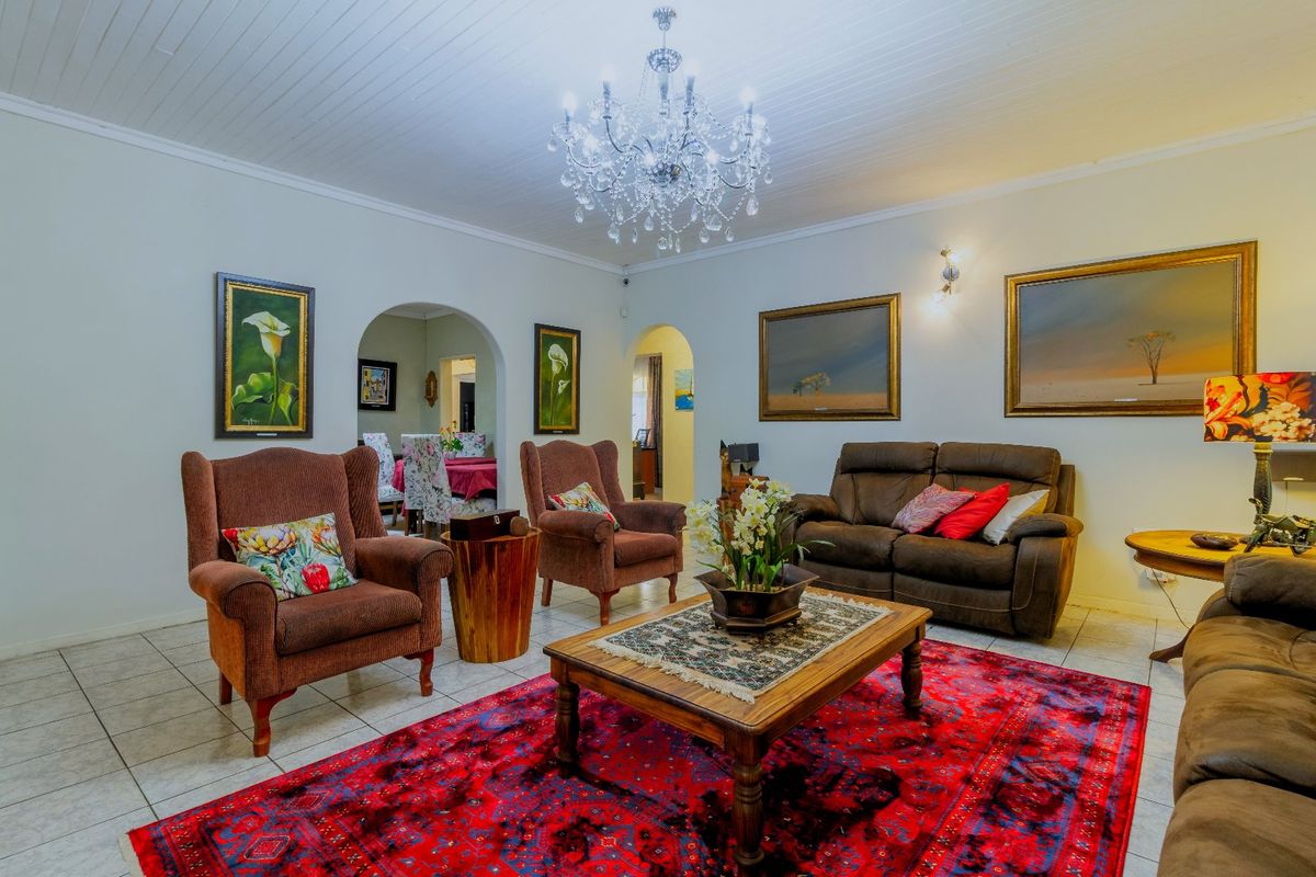 Spacious living area featuring tiled flooring, a classic chandelier, and arched doorways leading to adjacent rooms, creating an open and inviting atmosphere.