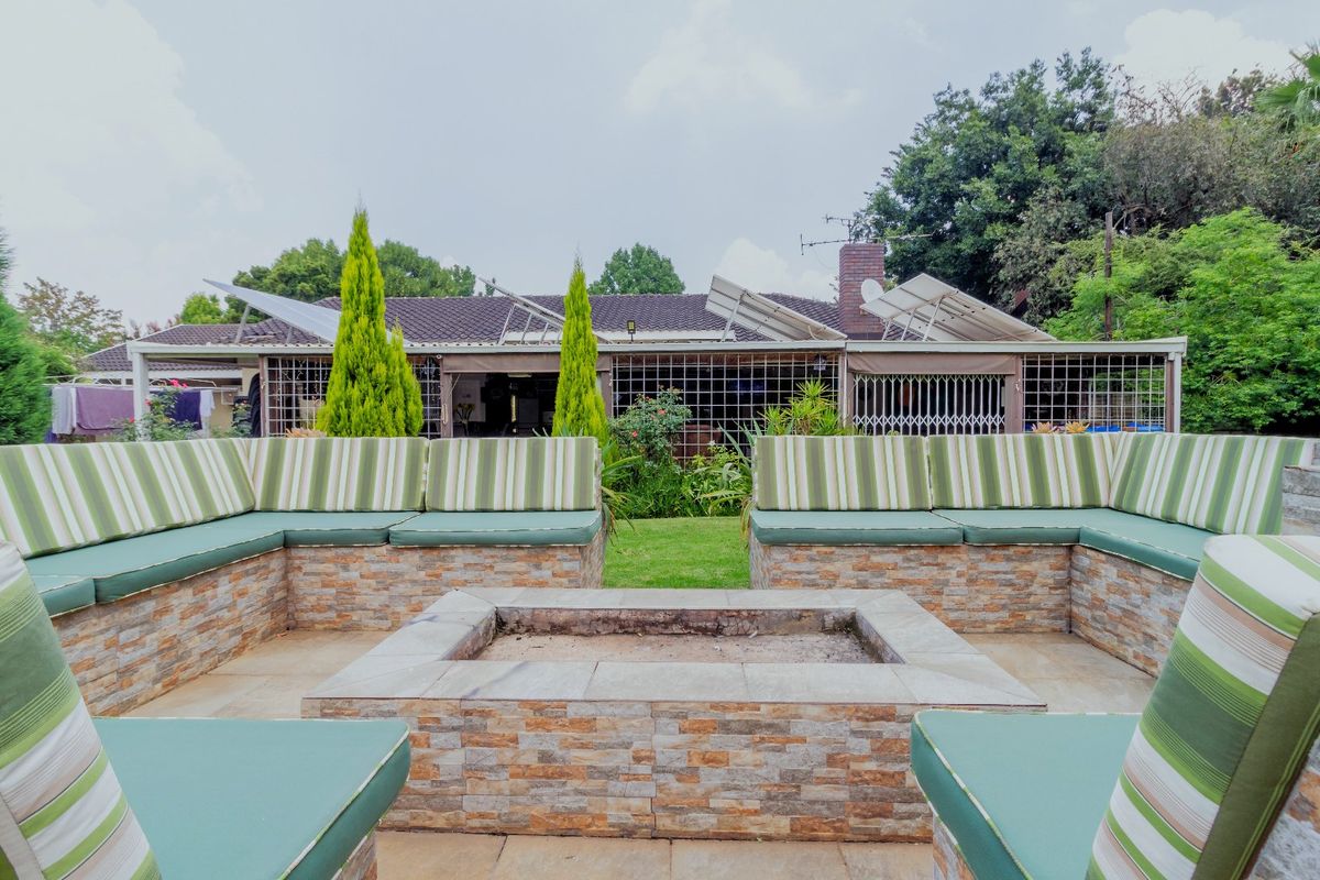 Outdoor entertainment area featuring a built-in stone fire pit with integrated seating, overlooking the rear garden and main building structure.