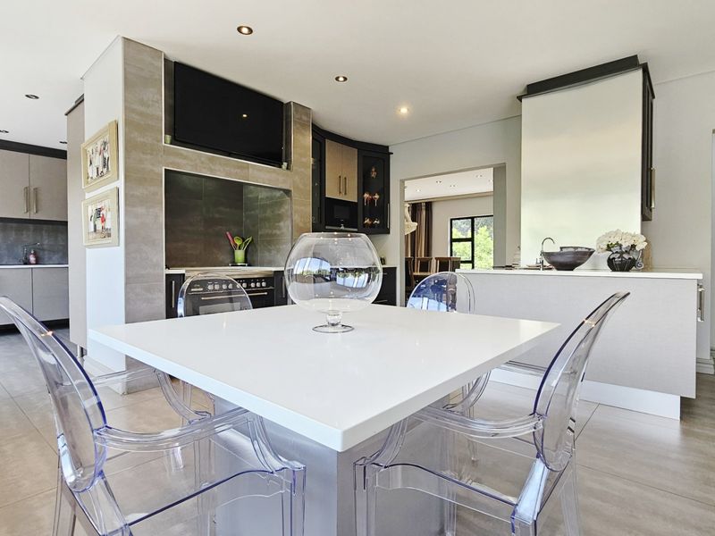 Modern open-plan kitchen and dining area featuring sleek cabinetry, integrated appliances, a central island, and recessed lighting throughout the space.