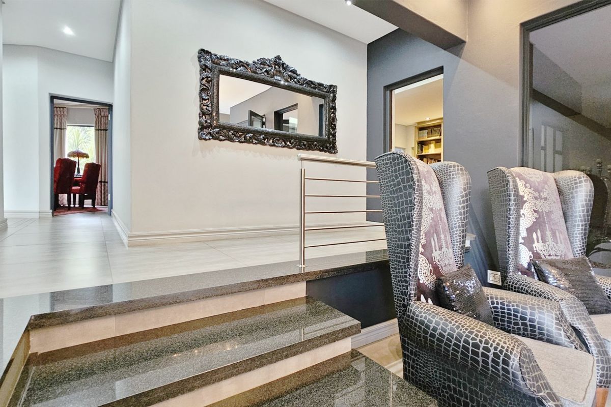 A sophisticated living area featuring a polished granite staircase with a modern stainless steel balustrade and elegant tiled flooring.