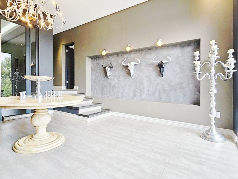 A spacious and modern entrance hall featuring large format floor tiles, a striking recessed feature wall with accent lighting, and a stone staircase.