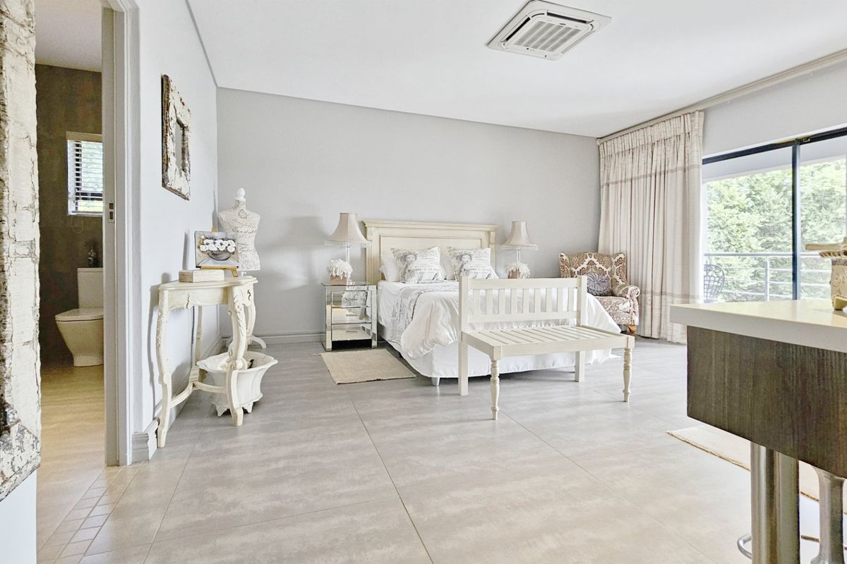 Spacious bedroom featuring large format floor tiles, recessed ceiling air conditioning, and direct access to an en-suite bathroom and private balcony.