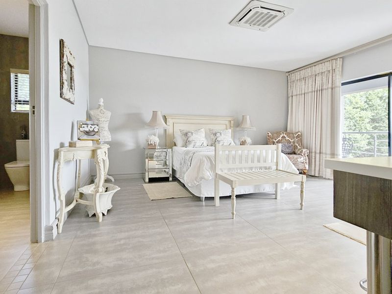 Spacious bedroom featuring large format floor tiles, recessed ceiling air conditioning, and direct access to an en-suite bathroom and private balcony.