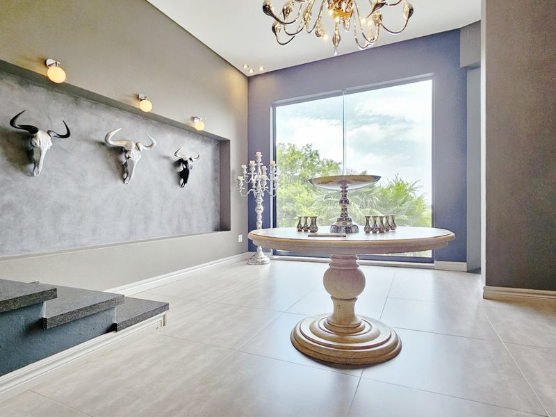 A spacious and modern entrance hall featuring large format floor tiles, a striking recessed wall niche, and a large window providing natural light.
