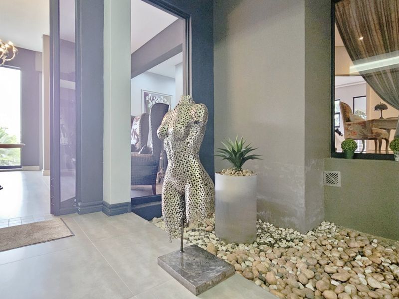 Modern entrance hall featuring tiled flooring, glass sliding doors, and a decorative pebble bed feature, creating a sophisticated and welcoming transition space.