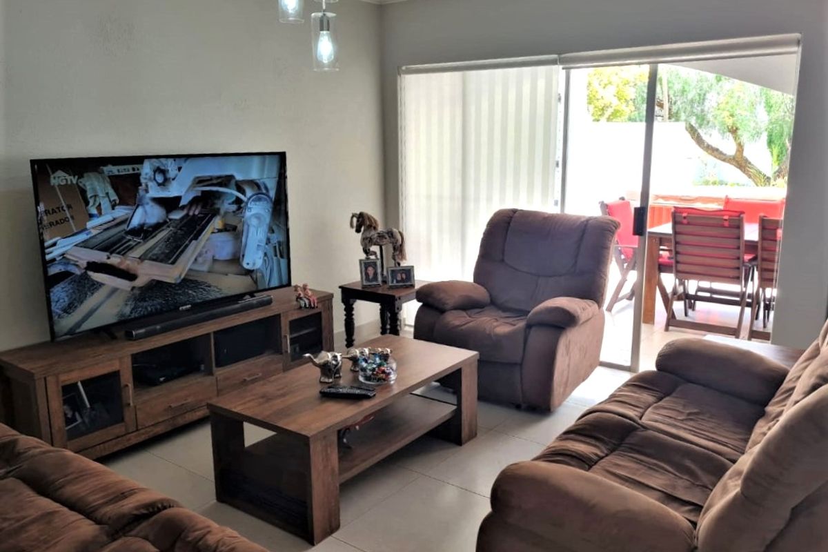 A comfortable living room featuring tiled flooring, modern pendant lighting, and a large sliding glass door providing direct access to the outdoor patio area.