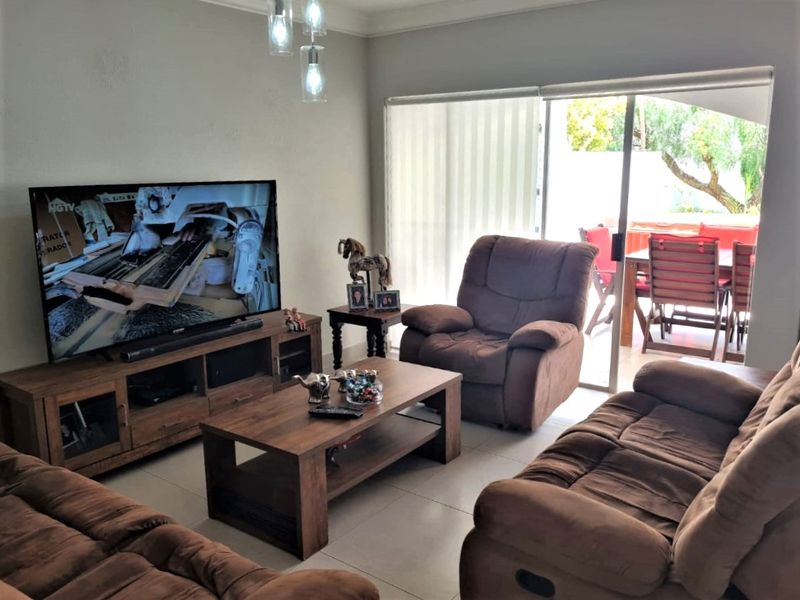 A comfortable living room featuring tiled flooring, modern pendant lighting, and a large sliding glass door providing direct access to the outdoor patio area.