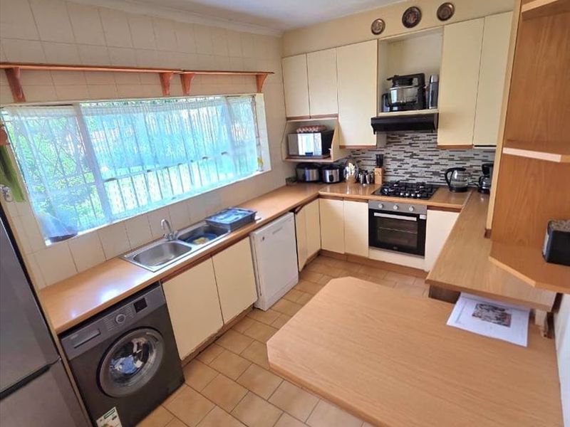 Functional kitchen featuring built-in cabinetry, gas hob, oven, and a breakfast nook, with tiled flooring and backsplash throughout.