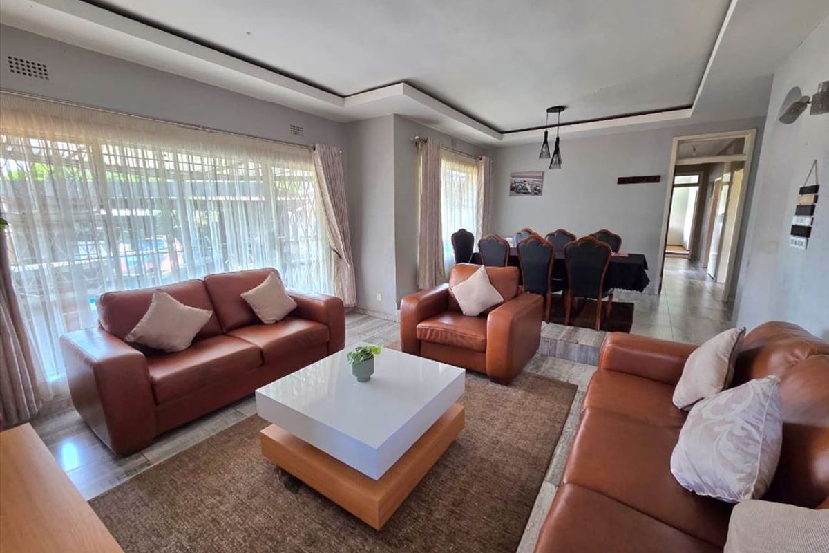 Spacious open-plan living and dining area featuring tiled flooring, recessed ceiling details, and large sliding doors providing natural light.