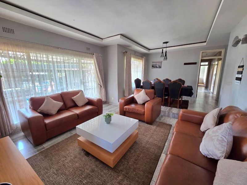 Spacious open-plan living and dining area featuring tiled flooring, recessed ceiling details, and large sliding doors providing natural light.