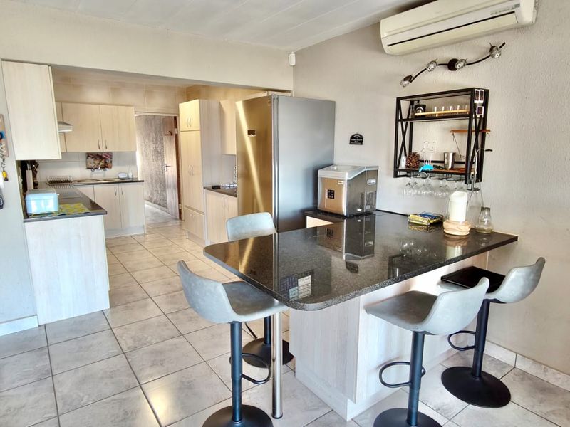 Open plan kitchen featuring a breakfast bar with granite countertops, light wood cabinetry, and integrated air conditioning unit.
