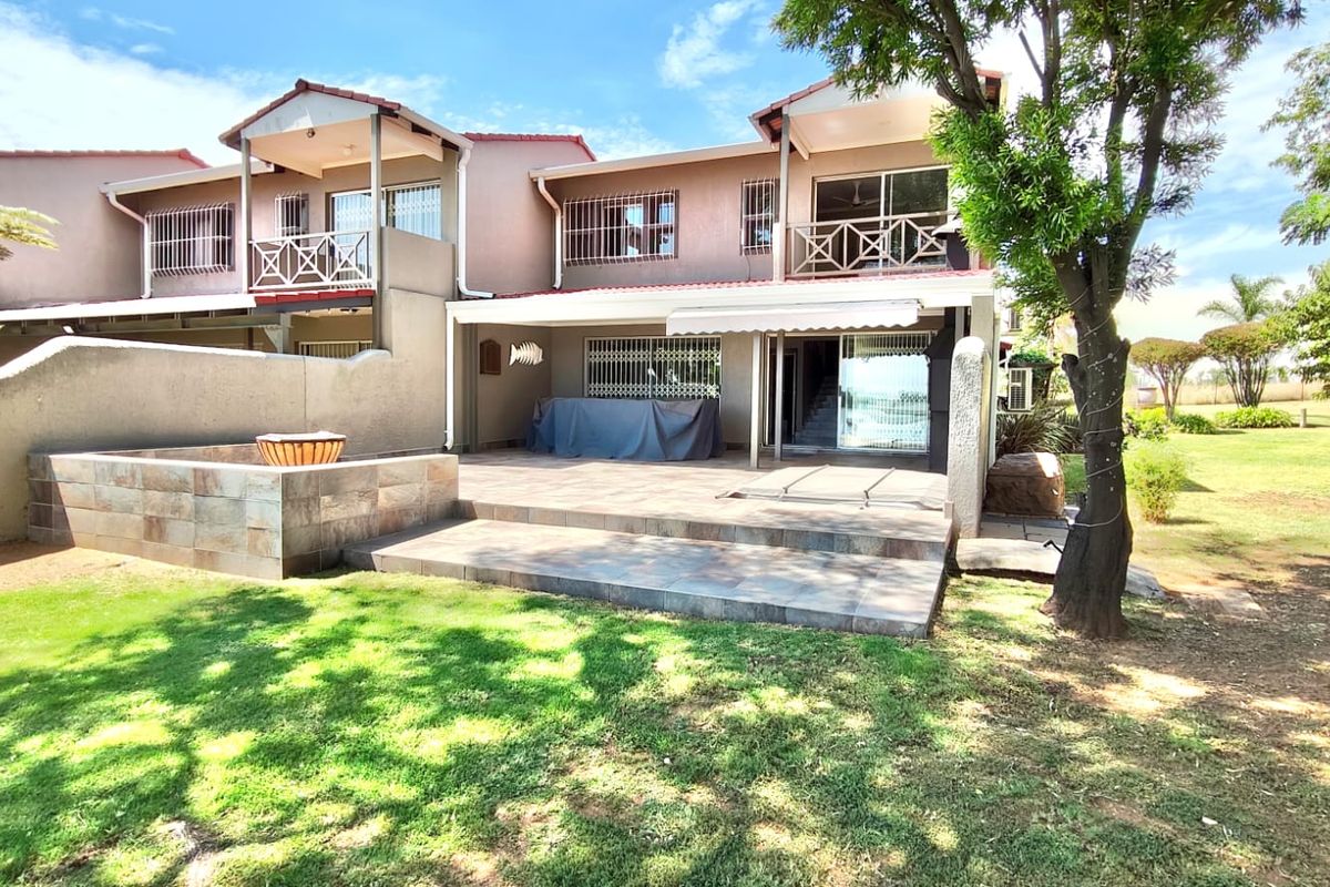 A spacious rear patio area featuring tiled flooring, a retractable awning, and direct access to a private garden space.