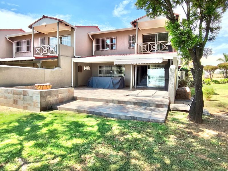 A spacious rear patio area featuring tiled flooring, a retractable awning, and direct access to a private garden space.