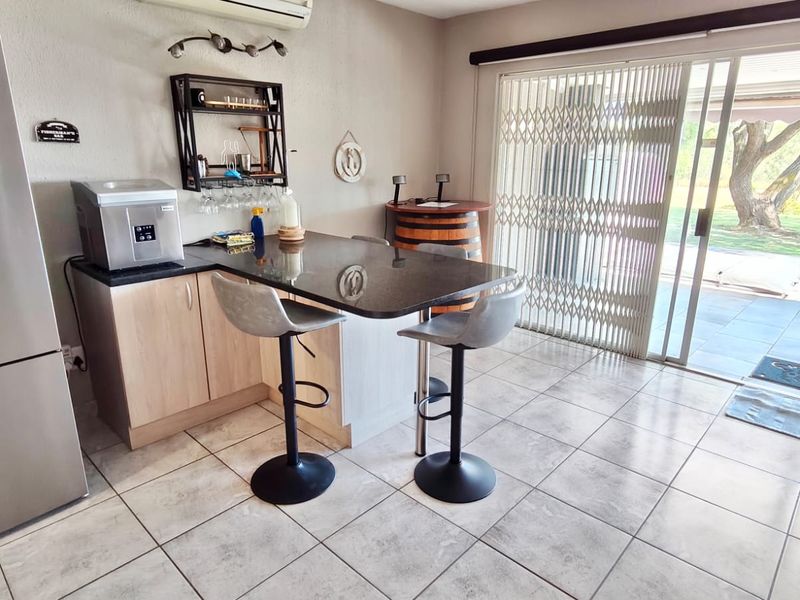 A bar area featuring a built-in counter with a dark stone top, tiled flooring, and sliding glass doors leading to an outdoor patio.