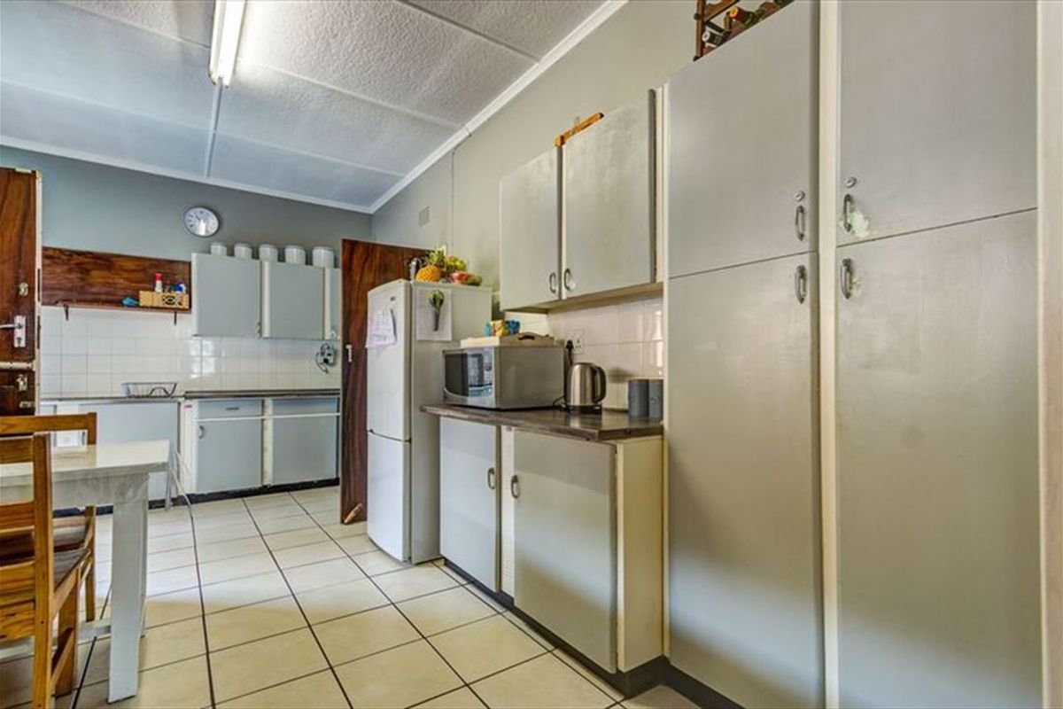A functional kitchen featuring tiled flooring, ample built-in cabinetry, and laminate countertops, offering a dated aesthetic ready for modernization.