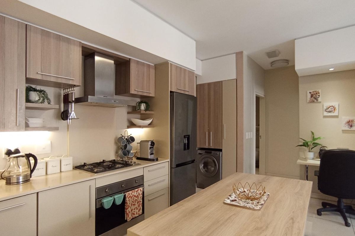 Modern kitchen featuring light wood cabinetry, stone countertops, integrated appliances, and a gas hob with an extractor fan.