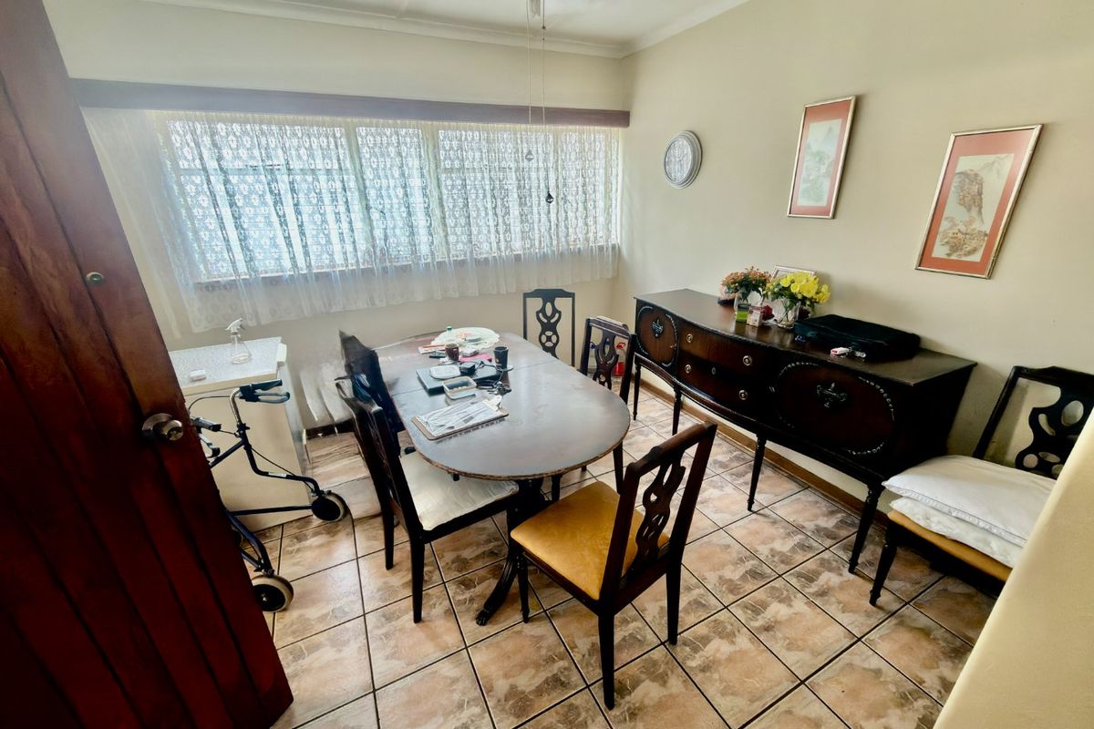 A dining room featuring tiled flooring and a large window, providing a functional space for meals.