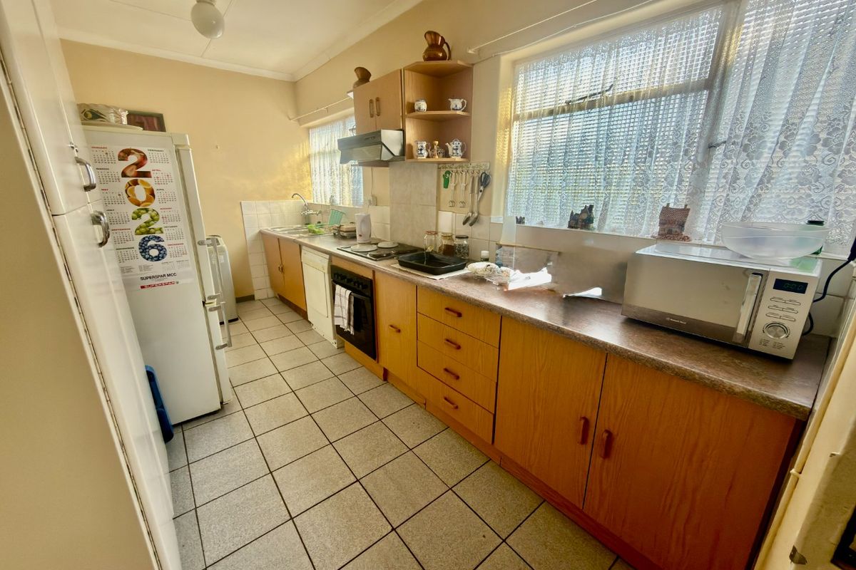 A functional kitchen featuring laminate cabinetry, tiled flooring, and a built-in oven, offering a dated aesthetic ready for modern updates.