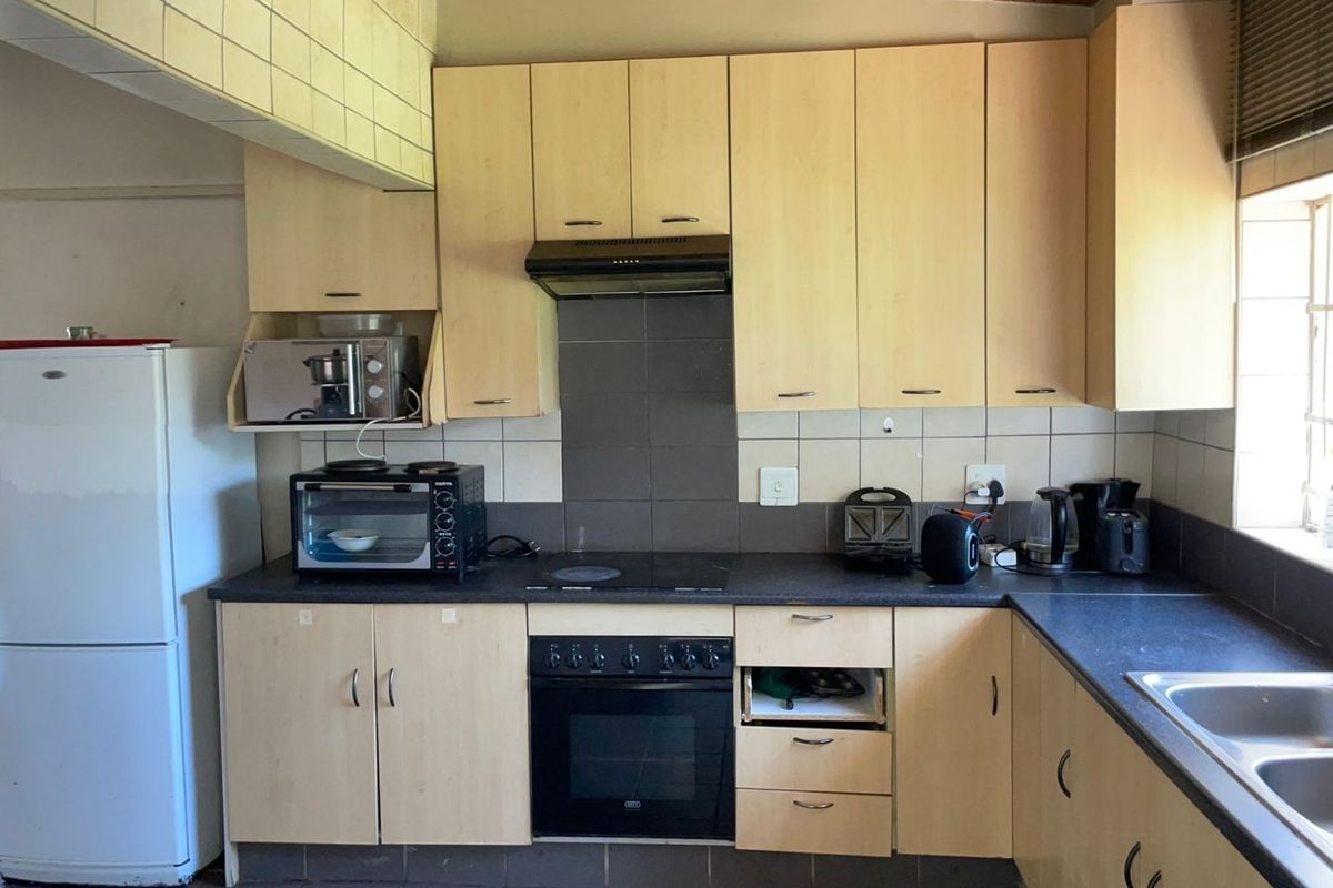 A functional kitchen featuring laminate cabinetry, built-in oven, electric hob, and double bowl sink, with a timber ceiling and tiled splashback.