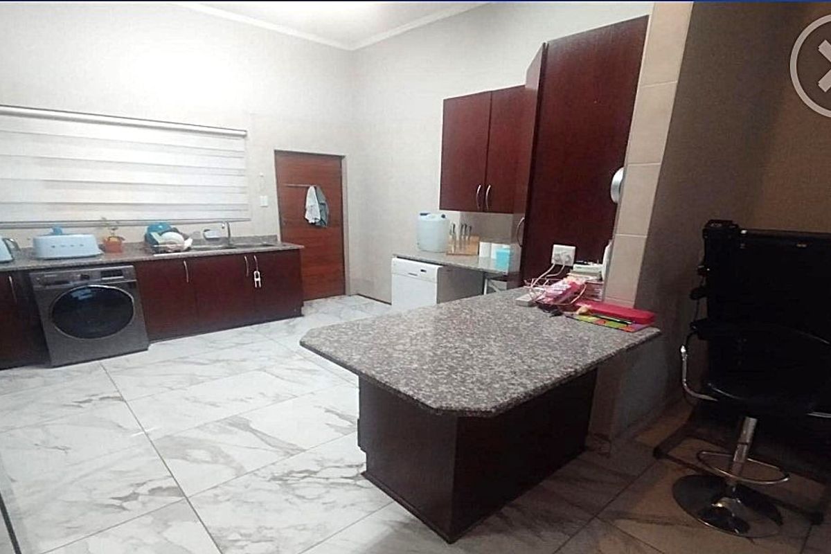 A functional kitchen featuring dark wood cabinetry, granite countertops, a breakfast bar, and tiled flooring.