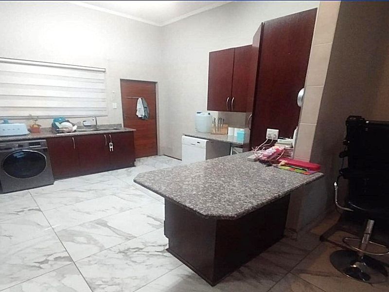 A functional kitchen featuring dark wood cabinetry, granite countertops, a breakfast bar, and tiled flooring.
