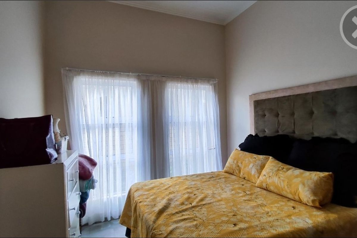 A bedroom featuring a large window with sheer curtains, providing natural light to the space.