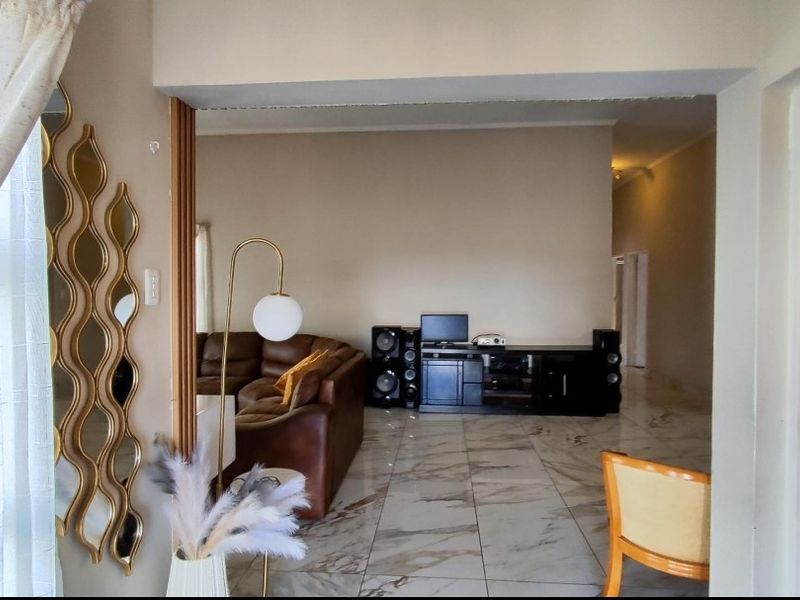 A view into a living area featuring polished marble-look floor tiles and a wide transition between rooms.