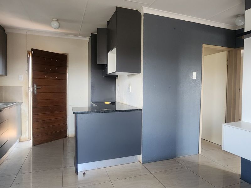 Open plan living area featuring a modern kitchen with dark cabinetry, granite countertops, and tiled flooring throughout the space.