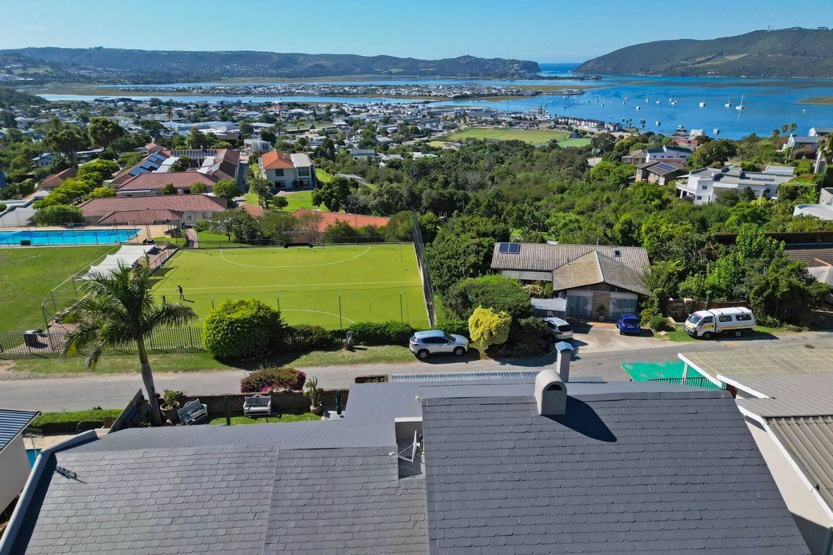 Aerial view of the property showing the tiled roof, chimney, and solar panels, with a scenic outlook over the surrounding neighbourhood and estuary.