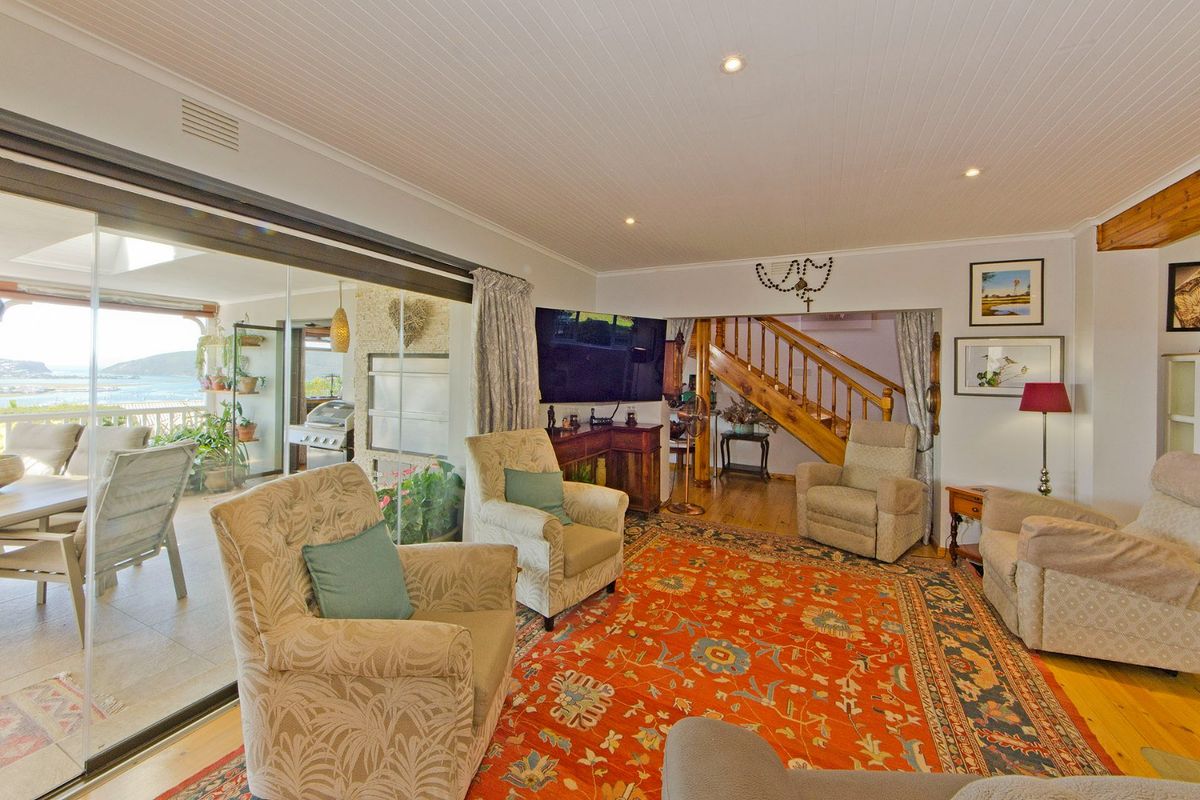 Spacious living room featuring timber flooring, a tongue and groove ceiling, and large sliding glass doors that open onto a covered patio with views.