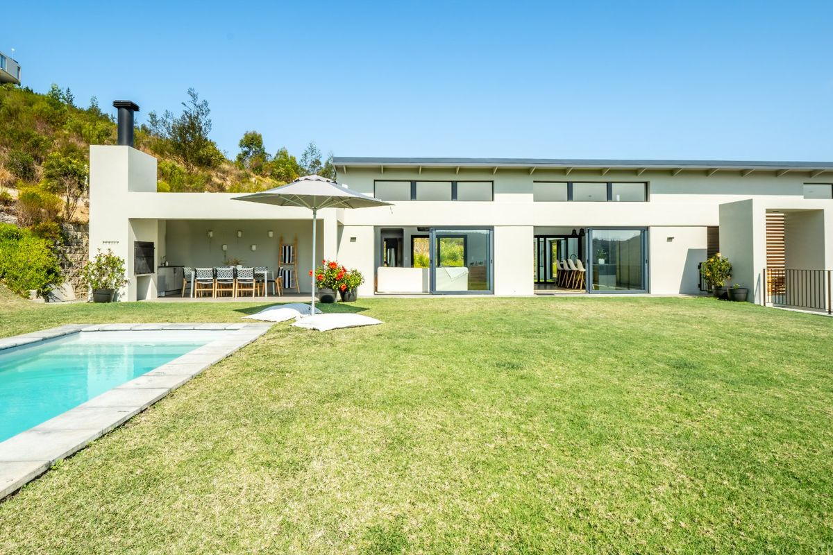 A modern rear exterior view featuring a swimming pool, a covered patio with a built-in fireplace, and large sliding glass doors leading indoors.