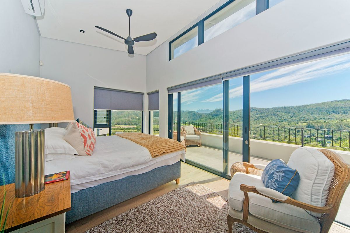 Spacious bedroom featuring high ceilings, a ceiling fan, air conditioning, and large sliding glass doors opening onto a private balcony with scenic mountain views.