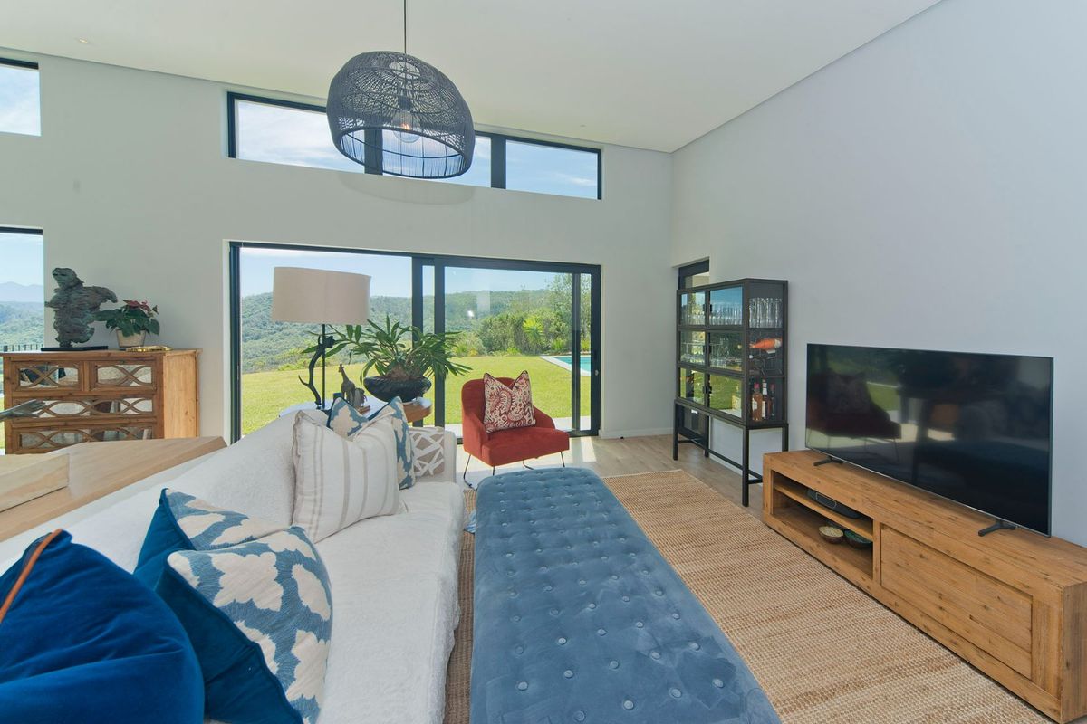 Spacious living room featuring high ceilings, large sliding glass doors, and clerestory windows that provide abundant natural light and scenic views of the garden.