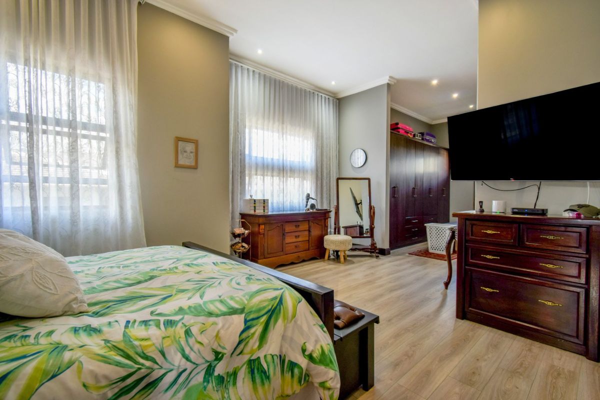A spacious bedroom featuring modern laminate flooring, built-in cupboards, and recessed downlighting, creating a comfortable and well-maintained living space.