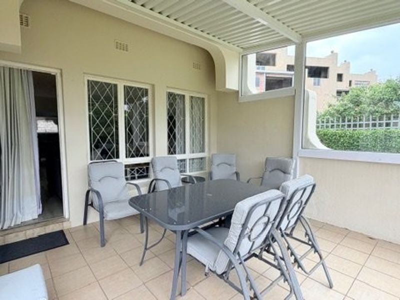Covered patio area featuring tiled flooring and a louvred roof, providing a functional outdoor space for dining and relaxation.