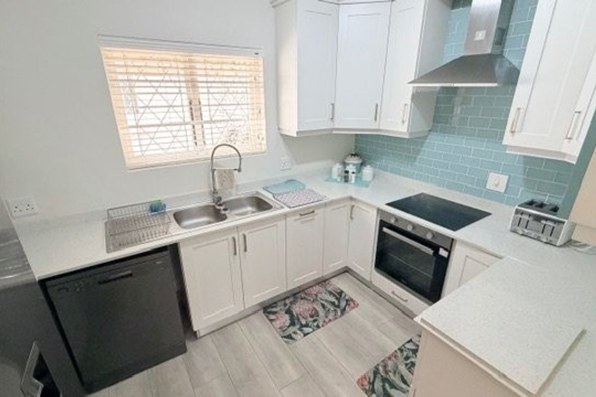 A well-maintained kitchen featuring white shaker-style cabinetry, quartz countertops, a light blue subway tile backsplash, and integrated stainless steel appliances.