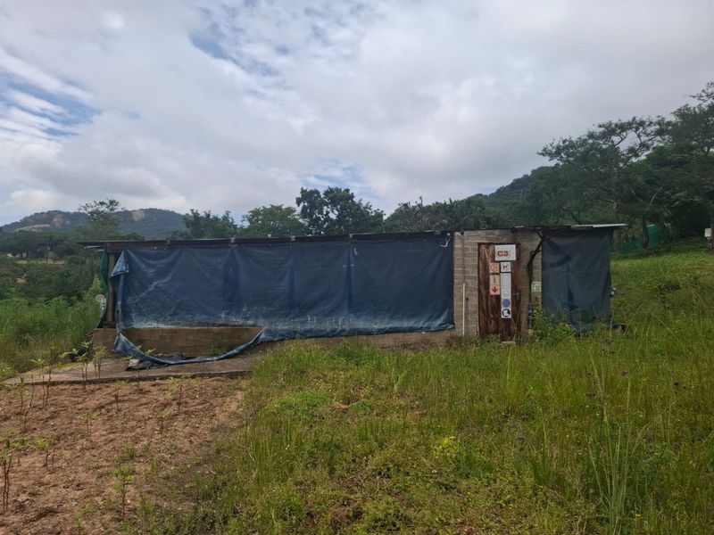 A basic utility structure on the farm property featuring concrete block walls and a tarp-covered enclosure.
