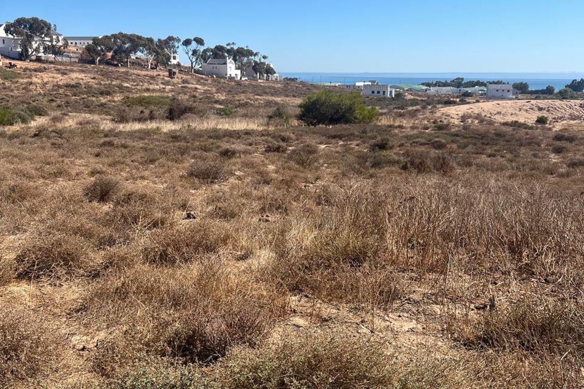 A wide-angle view of the vacant residential land, showcasing the natural landscape and distant coastal horizon.