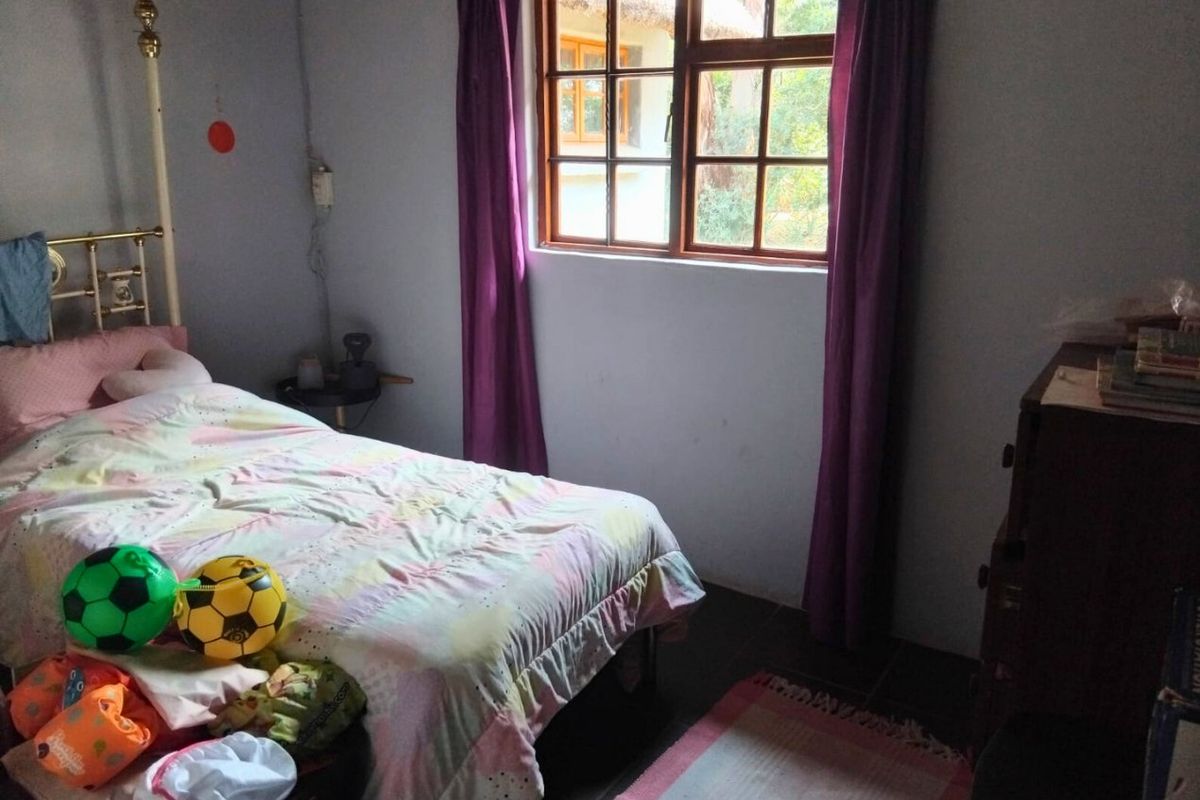 A functional bedroom featuring a timber-framed window and tiled flooring, offering a simple and practical living space.