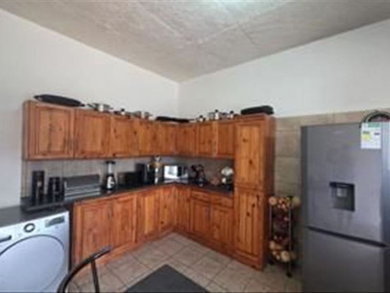 A functional kitchen featuring traditional wooden cabinetry, tiled backsplash, and tiled flooring, providing ample storage and workspace for daily culinary activities.
