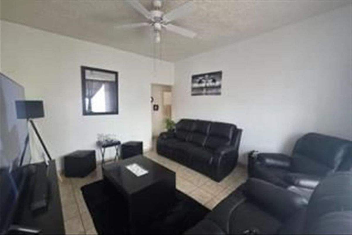 A living room featuring tiled flooring and a ceiling fan, providing a functional space for relaxation.