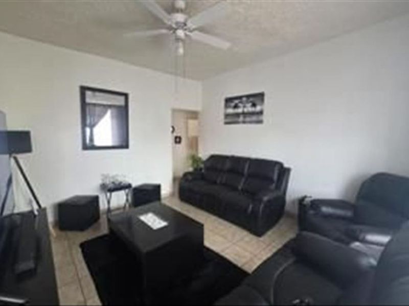 A living room featuring tiled flooring and a ceiling fan, providing a functional space for relaxation.