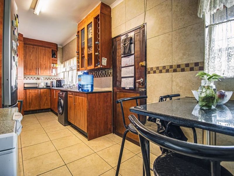A functional kitchen featuring wooden cabinetry, granite countertops, and ceramic tiled flooring, offering a traditional layout with ample storage space.