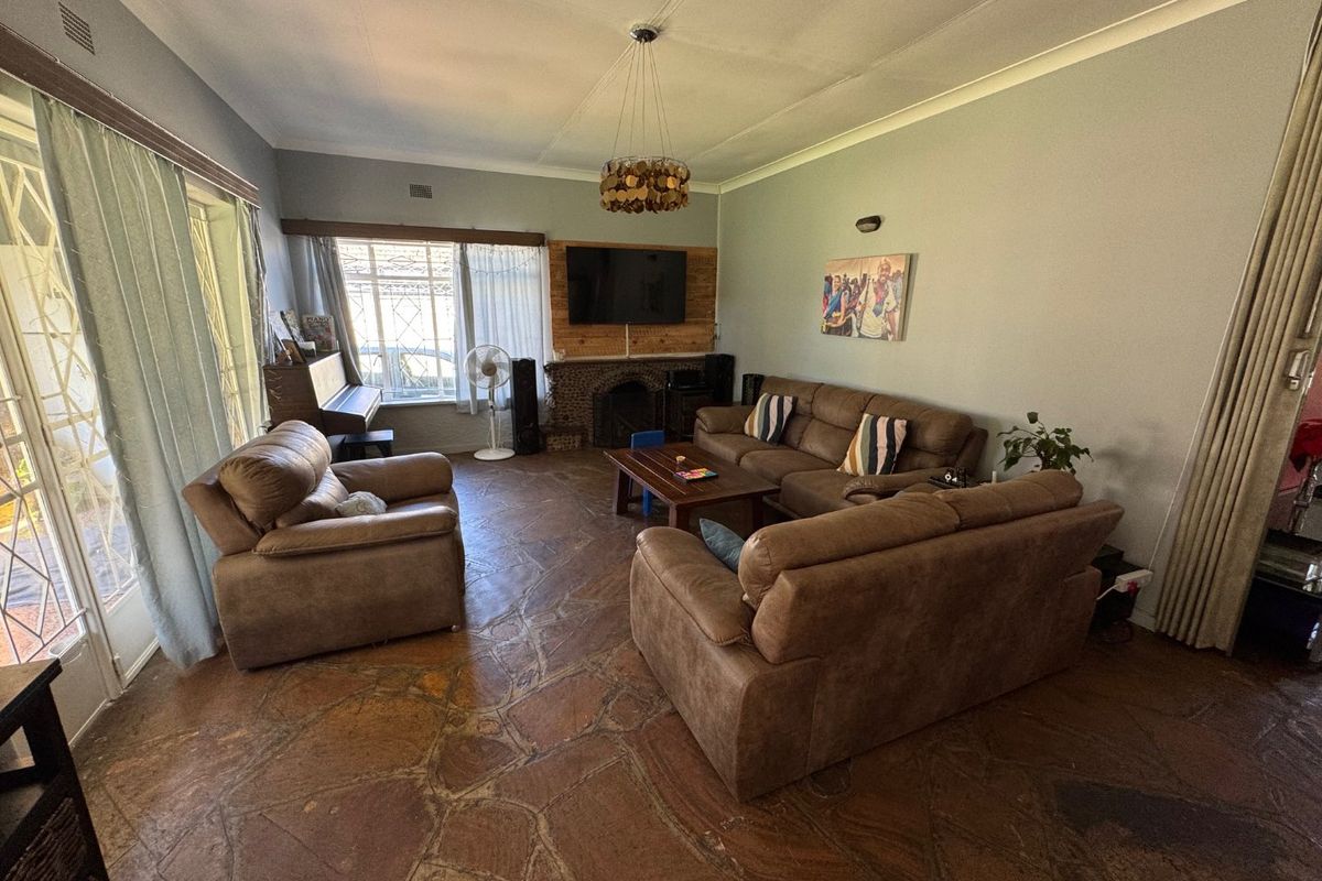 Spacious living room featuring unique natural stone flooring, a built-in fireplace, and large windows providing ample natural light.
