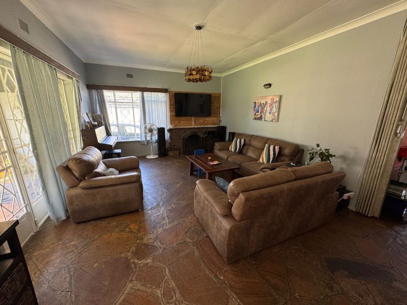 Spacious living room featuring unique natural stone flooring, a built-in fireplace, and large windows providing ample natural light.