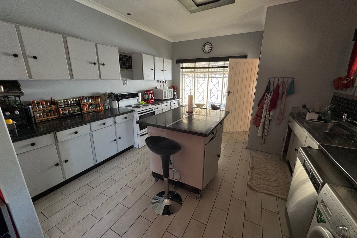 Functional kitchen featuring a central island, ample cabinetry, tiled flooring, and integrated appliance space, providing a practical layout for daily meal preparation.