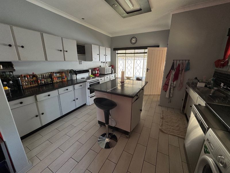 Functional kitchen featuring a central island, ample cabinetry, tiled flooring, and integrated appliance space, providing a practical layout for daily meal preparation.
