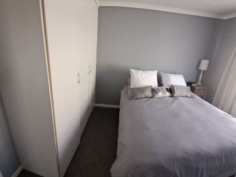 A functional bedroom featuring built-in cupboards and neutral wall finishes, providing a comfortable and practical living space.